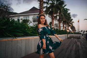  girl at sunset on the waterfront with palm trees in a green dress