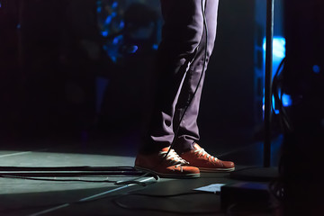 A singer standing on the stage during a concert wearing sneakers