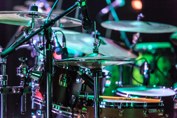 A full set of drums standing on a stage in colourful lights