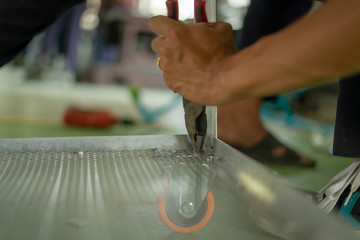 Close-up of a hand with dark skin tone using a pair of pliers 