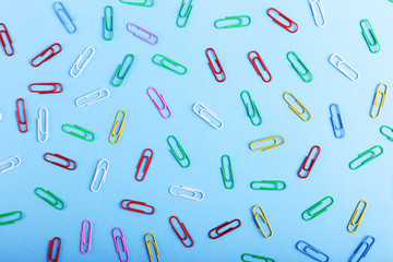 Fototapeta na wymiar Multicolored paper clips on a blue background, pattern, copy space.