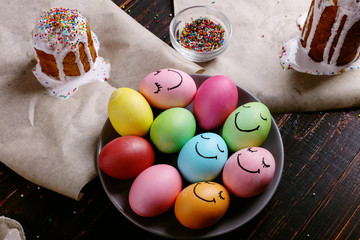 Easter baking with icing and colored powder and eggs. Preparing for the holiday on the kitchen table, on a dark background.