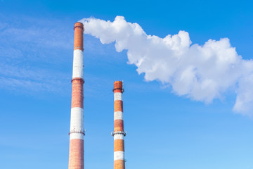 The pipe of the plant emits harmful substances into the atmosphere. Close-up on a sky background.