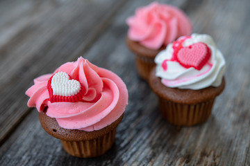 pink and white muffins with heart on wooden ground