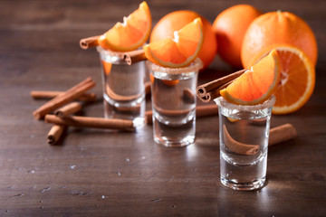 Glasses of tequila with orange slices and cinnamon sticks .