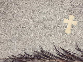 Ash Wednesday concept - A religious cross formed out of ashes. There’s a dry palm leaf under them.