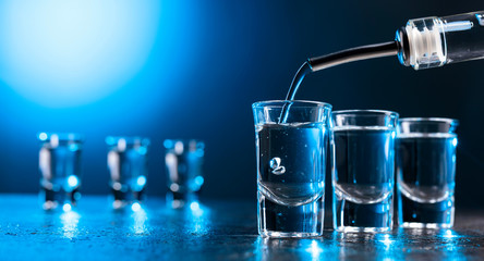 Vodka poured into a glass lit with blue backlight.