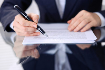 Unknown female hands with pen over document of contract. Agreement signing or business concept