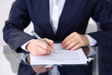 Unknown female hands with pen over document of contract. Agreement signing or business concept