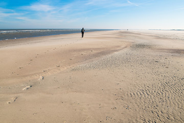 Wind, Sand und Meer - Spaziergängerin am einsamen Strand im Norden der Insel Norderney