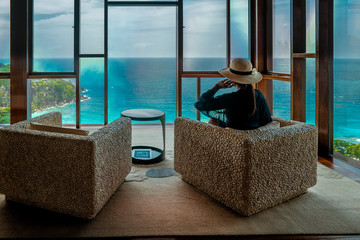 woman by windown in luxury beach chairs looking out over ocean of Praslin Seychelles