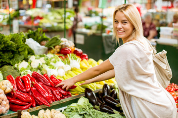 Cute young woman buying vegetables at the market