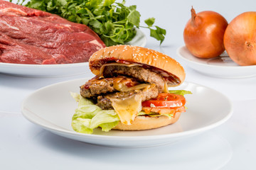 cheeseburger, chicken cutlet, bacon, tomatoes and slices of cheese, dressed with sauce and green salad for a restaurant menu on a white isolated background