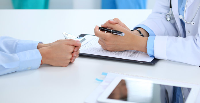 Doctor and patient discussing something, just hands at the table, white background