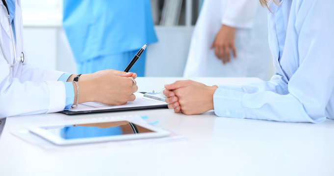 Doctor and patient discussing something, just hands at the table, white background