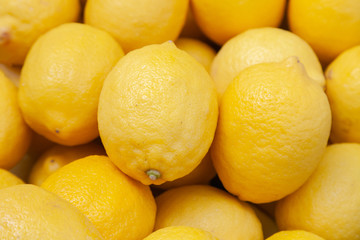 Closeup pile of fresh yellow lemons on counter at the farmers market. New Year fruit concept, fresh squeezed vitamin juice, healthy foods