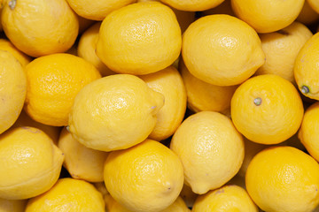 Closeup pile of fresh yellow lemons on counter at the farmers market. New Year fruit concept, fresh squeezed vitamin juice, healthy foods
