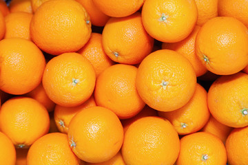 Many tasty ripe orange mandarins are piled on counter at the farmers market. New Year fruit concept, fresh squeezed vitamin juice, healthy foods