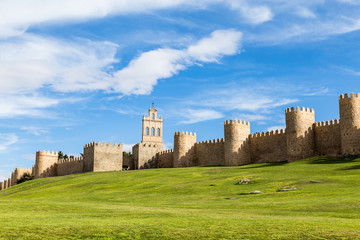 Fototapeta na wymiar View of the medieval city walls surrounding the city of Avila, Spain, and the green lawn in front of Puerta del Carmen. Called the Town of Stones and Saints, Avila is a UNESCO World Heritage Site