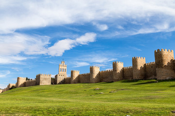 View of the medieval city walls surrounding the city of Avila, Spain, and the green lawn in front of Puerta del Carmen. Called the Town of Stones and Saints, Avila is a UNESCO World Heritage Site © giusparta