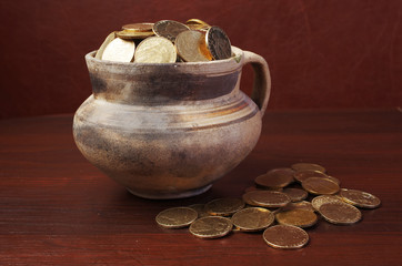 Gold coins in a clay pot. Close-up. Ukrainian hryvnia.