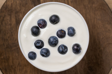 Yogurt with resh blueberries, in bowl over old wood background.