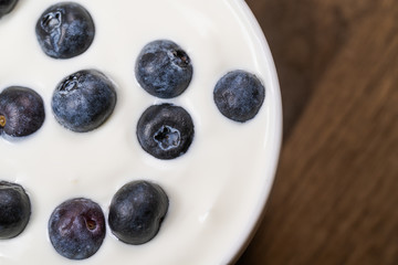 Yogurt with resh blueberries, in bowl over old wood background.