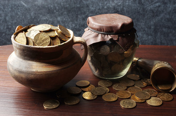 Gold coins in a pot and in a glass jar. Ukrainian hryvnia.