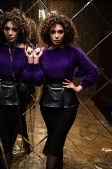 Sexy model with a curly hair, mirror background, shooting in the interior, bright girl, fashion model