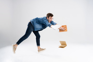 front view of going handsome man carries a stack of books. walking young guy isolated over white. Student dropped the heavy books.