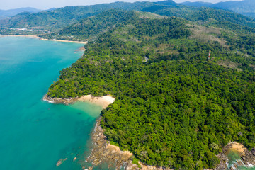Fototapeta na wymiar Aerial drone view of a beautiful small sandy beach surrounded by lush, green evergreen forest