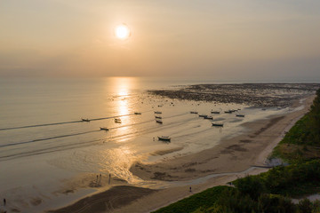 Obraz premium Aerial drone view of a tropical sunset over the ocean with traditional longtail boats at anchor (Pakarang Cape, Phang Nga, Thailand)