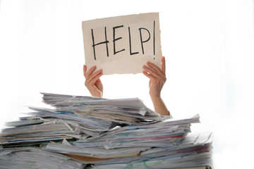 Person under a pile of papers with a hand holding a sign of help. Accounting.