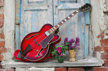 Jazz guitar in the window opening with a bouquet of flowers
