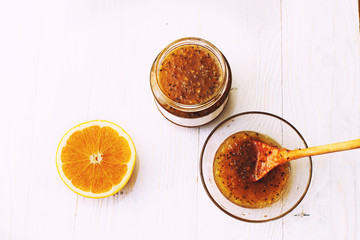 gooseberry and orange jam in a glass bowl with a wooden spoon on a white background