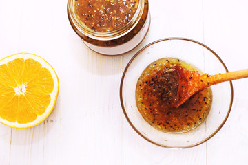 gooseberry and orange jam in a glass bowl with a wooden spoon on a white background