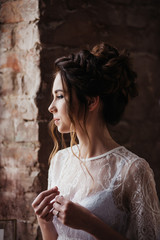 Portrait of a beautiful bride. Charges in the morning at home near brick wall. Classical wedding.