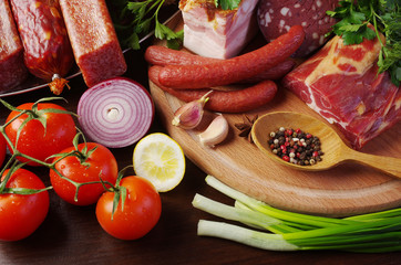 Sausage, salami, ham and vegetables on the kitchen board