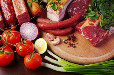 Meat products, vegetables and spices on the kitchen board.