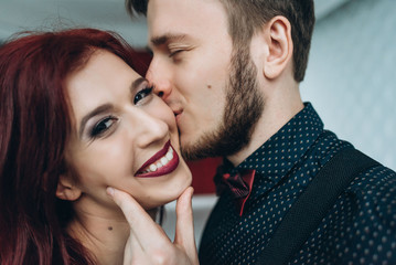 Naklejka premium Happy attractive smiling couple. Handsome young man kisses his attractive redhaired girlfriend
