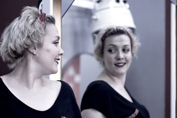 Blonde woman looking in the mirror of a hairdresser