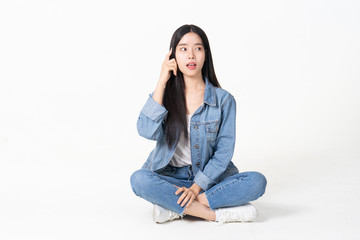 Thinking asian woman sitting on floor isolated on white background.Asian female model smiling looking up.woman pointing fingers away while sitting on a floor with legs crossed isolated