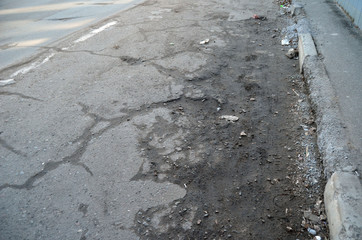 Poor condition of the road surface. Winter season. Hole in the asphalt, risk of movement by car, bad asphalt, dangerous road, potholes in asphalt.  Kiev,Ukraine