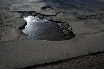 Poor condition of the road surface. Winter season. Hole in the asphalt, risk of movement by car, bad asphalt, dangerous road, potholes in asphalt.  Kiev,Ukraine