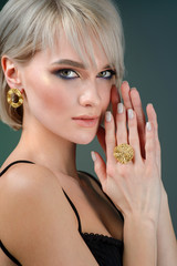 Stylish hairstyle and light makeup. Wearing earring and finger ring. Isolated on blue background