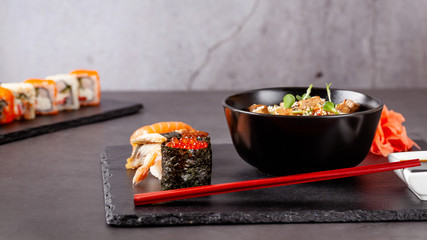 The concept of Japanese cuisine. Japanese lunch of noodles, sushi with shrimp, red caviar, eel, tuna. Soy sauce and red chinese sticks. background image. Top view, copy space