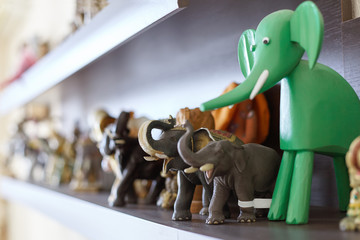 Figures of elephants on the shelf. Wooden, stone and ceramic statues, concept of happiness and luck...