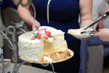 Kelnerka dzieli tort na przyjęciu weselnym.