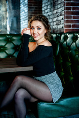 beautiful girl sitting on a sofa in a cafe and smiling