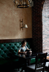 Obraz na płótnie Canvas beautiful girl reads an interesting book in a cafe